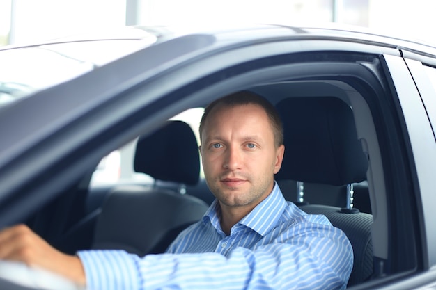 Confident businessman in full suit sitting in the luxe car.