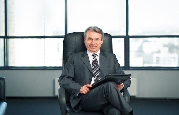 Confident businessman in office sitting on chair in office