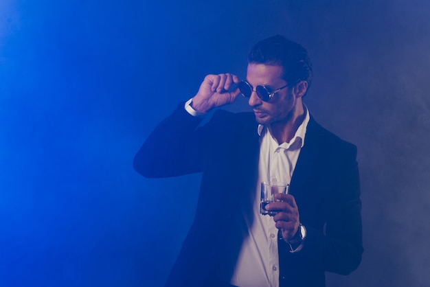 Confident businessman posing in the dark room