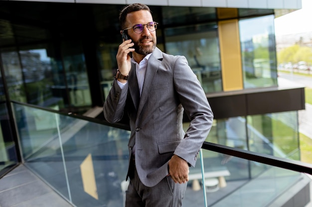 Confident Businessman Smiling in Sharp Suit Against Modern Glass Office Facade Generative AI