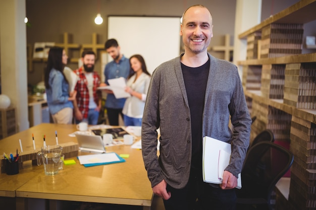 Confident businessman standing by table in creative office