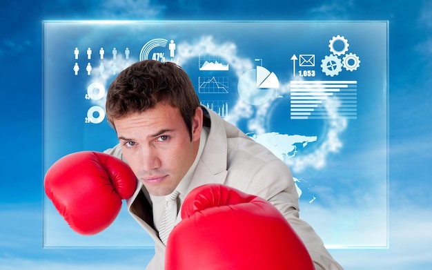 Confident businessman wearing boxing gloves against white cogs in the sky