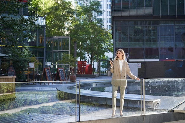 Confident businesswoman in beige suit standing in power pose in
city center