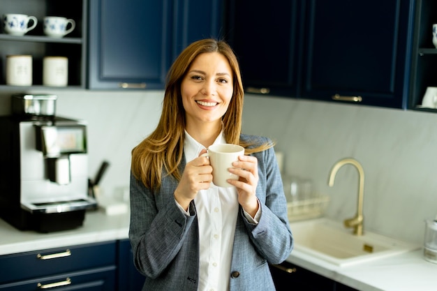 Confident Businesswoman Enjoying a Coffee Break in a Modern Office Kitchen