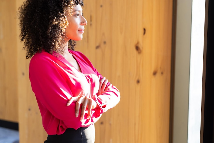 Photo confident businesswoman in red blouse standing with arms crossed looking outside