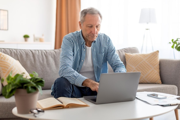 Confident casual mature using laptop at home