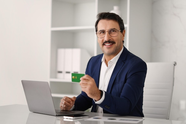 Confident caucasian adult businessman in suit at table with computer