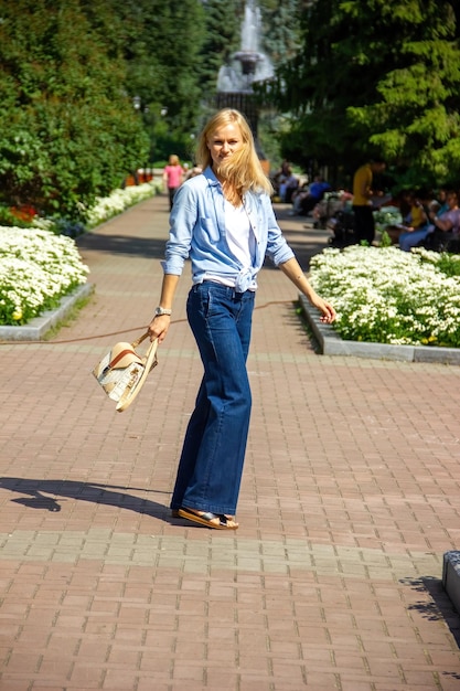 A confident Caucasian girl walks in the park in warm weather outdoors