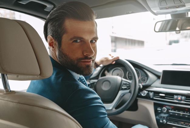 Confident caucasian man in suit sitting in his automobile