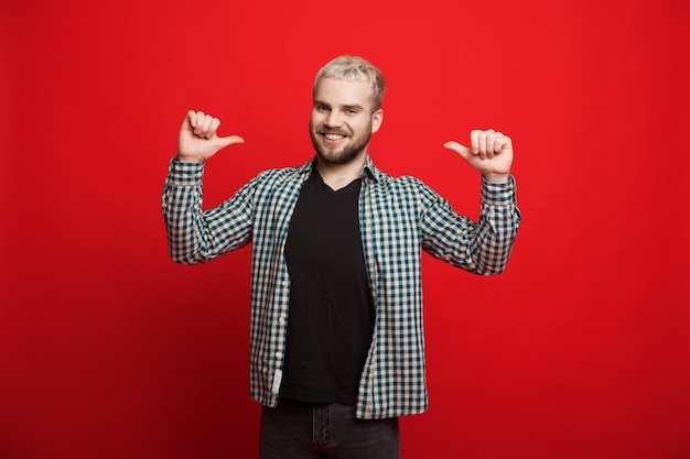 Confident caucasian man with blonde hair and beard is pointing to him while smiling