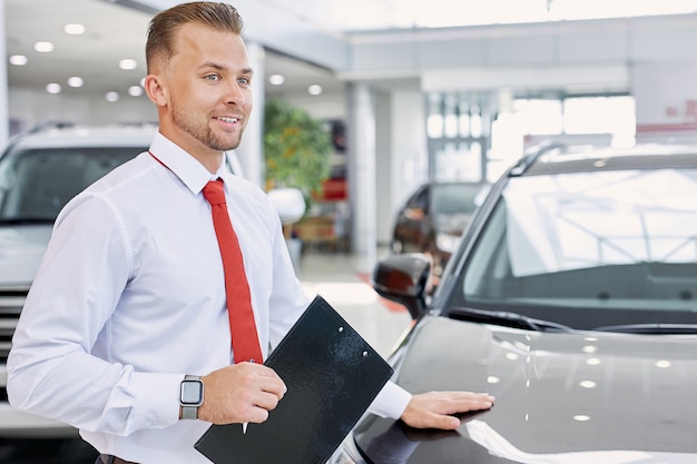 Concessionario di auto sorridente caucasico fiducioso al lavoro