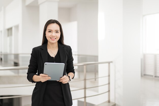Photo a confident cheerful southeast asian businesswoman professional in business suit with digital tablet