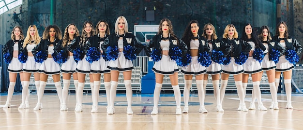 Confident cheerleaders posing in miniskirts holding pompoms showing team spirit