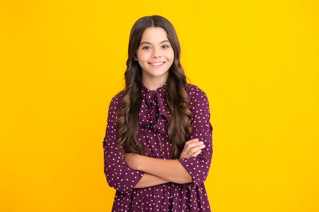 Confident child keep arms crossed isolated on yellow background empty space Little caucasian teenage girl 12 13 14 years old hold hands crossed Children studio portrait Childhood lifestyle