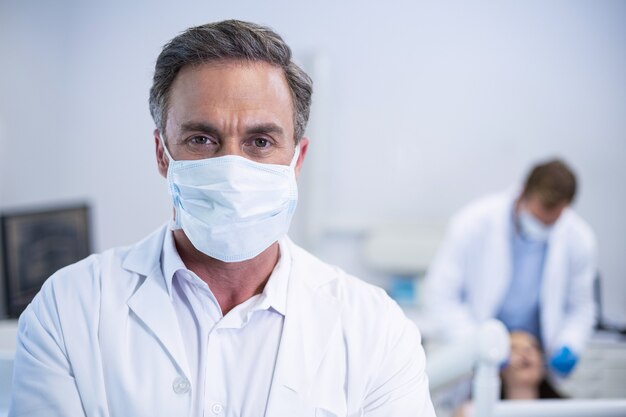 Confident dentist in surgical mask at dental clinic