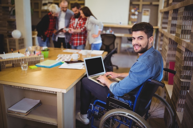 Foto uomo d'affari disabile sicuro che per mezzo del computer portatile allo scrittorio