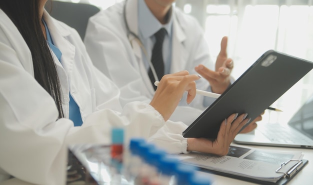 Confident doctor man holding a pill bottle and writing while talking with senior patient and reviewing his medication at office room