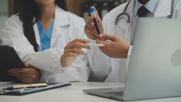 Confident doctor man holding a pill bottle and writing while talking with senior patient and reviewing his medication at office room