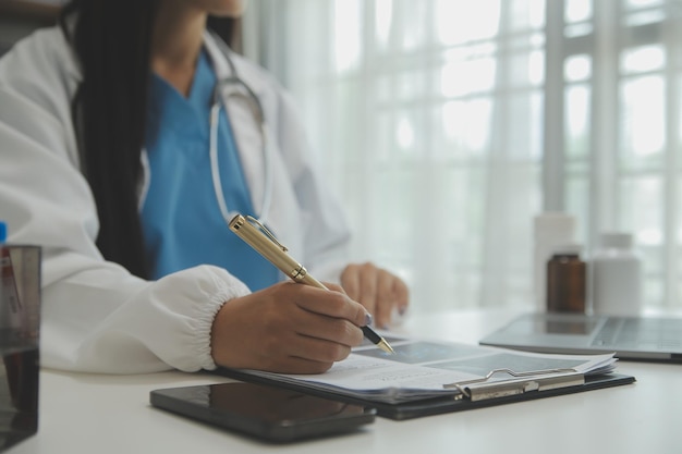 Confident doctor man holding a pill bottle and writing while talking with senior patient and reviewing his medication at office room