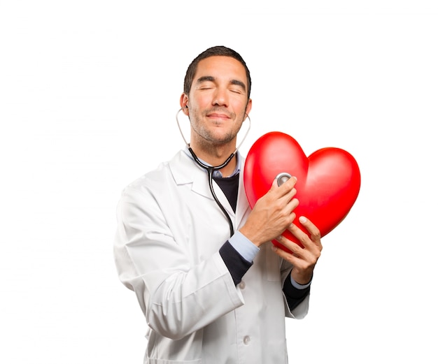 Confident doctor using a stethoscope against white background