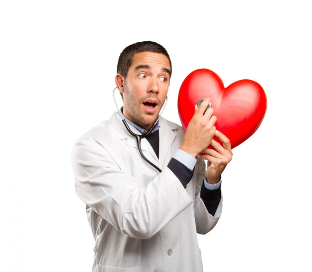 Confident doctor using a stethoscope against white background