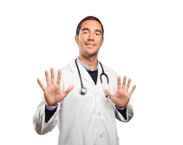 Confident doctor with keep calm gesture against white background