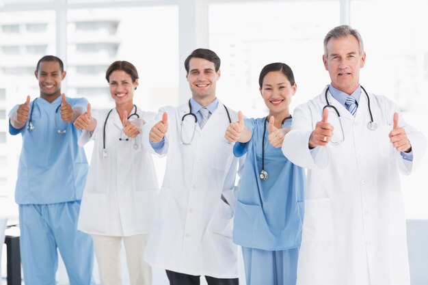 Confident doctors gesturing thumbs up at hospital