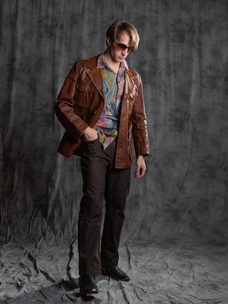 Confident dude in a colorful shirt and brown leather jacket a portrait in sunglasses in the studio o