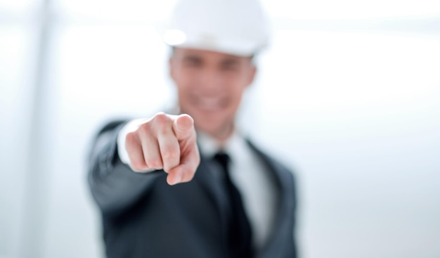 Confident engineer in helmet points finger at camera