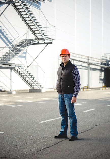 Confident engineer posing against big warehouse