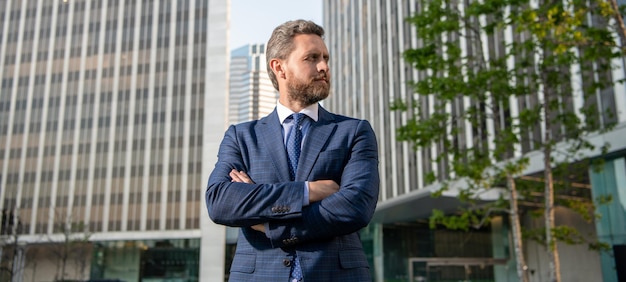 Confident entrepreneur in businesslike suit crossed hands outside the office, charisma.