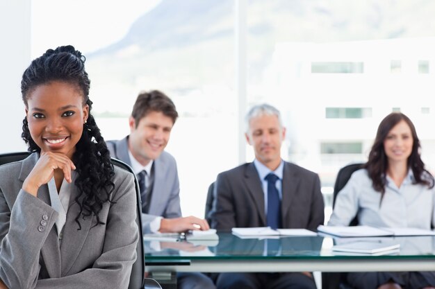 Confident executive sitting in a meeting room while her team is looking at her