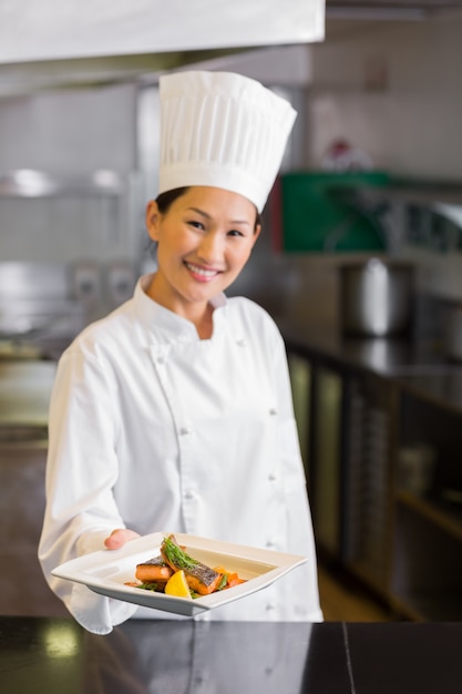 Уверенный женский шеф-повар, проведение приготовленные блюда на кухне