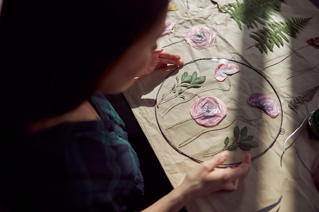 自信を持って女性の花屋が居心地の良いフラワーショップでドライフラワーを扱っています