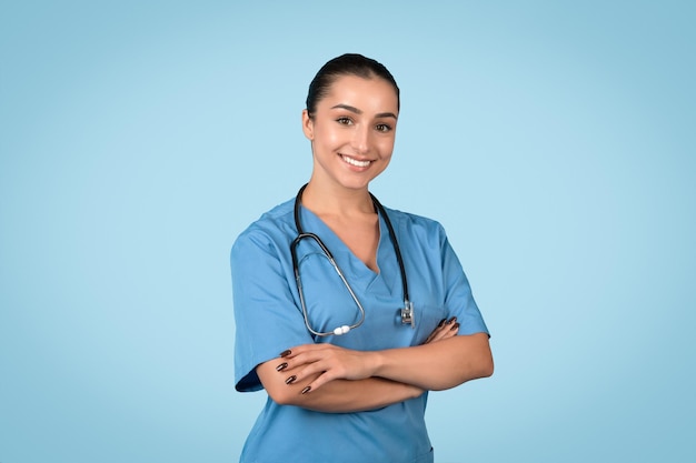 Confident female nurse in blue scrubs with arms crossed