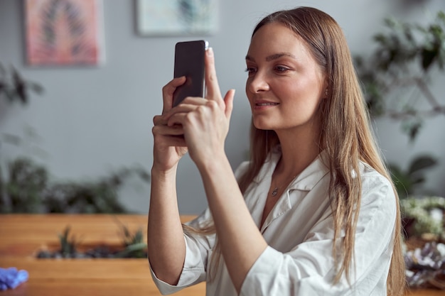 La donna femminile sicura sta prendendo la foto sul suo smartphone