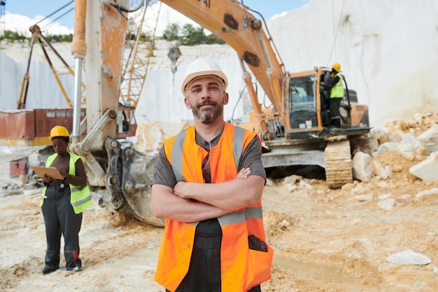 Confident foreman in reflective vest and safety helmet looking at camera