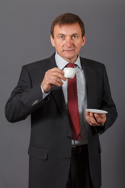 confident and friendly elegant handsome mature businessman taking a cup of coffee