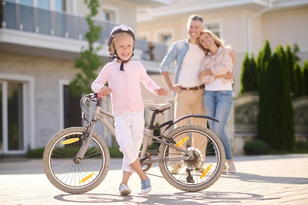 Confident girl with bike and happy parents