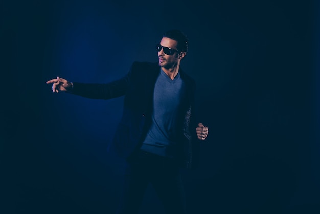 Confident guy with sunglasses posing in the dark room