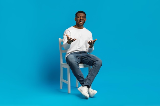 Confident handsome black guy sitting on chair gesturing