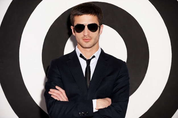 Photo confident handsome. handsome young man in formalwear keeping arms crossed while standing against black and white background