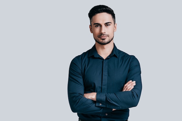 Confident and handsome. Handsome young man keeping arms crossed and looking at camera 