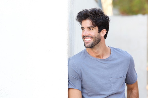 Confident handsome man standing outside by wall