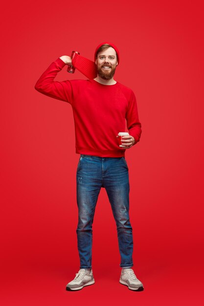 Confident hipster with cup and skateboard