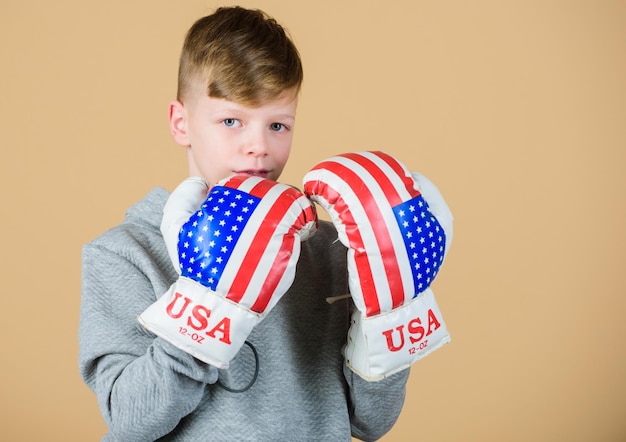 Confident in his strength Start boxing career Boy sportsman wear boxing gloves with usa flag American boxer concept Child sporty athlete practicing boxing skills Boxing sport Towards victory