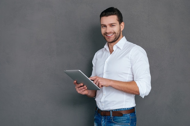 Confident IT professional. Handsome young man holding digital tablet and smiling