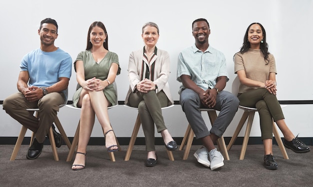 Confident and keen to prove their talent Portrait of a group of businesspeople sitting together in a line against a white wall