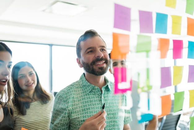 Confident leader discussing over adhesive notes with team at office