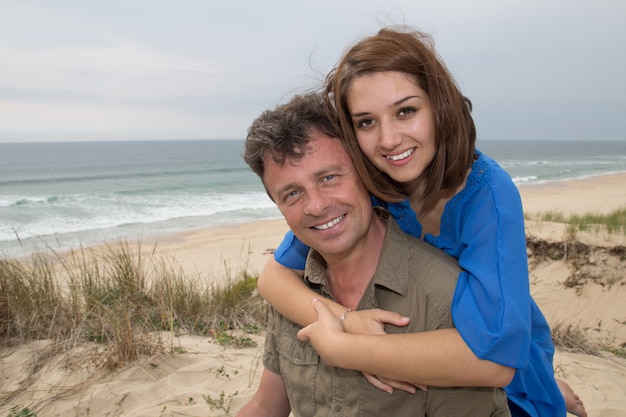 Уверенная и любящая пара обнимаются на пляже